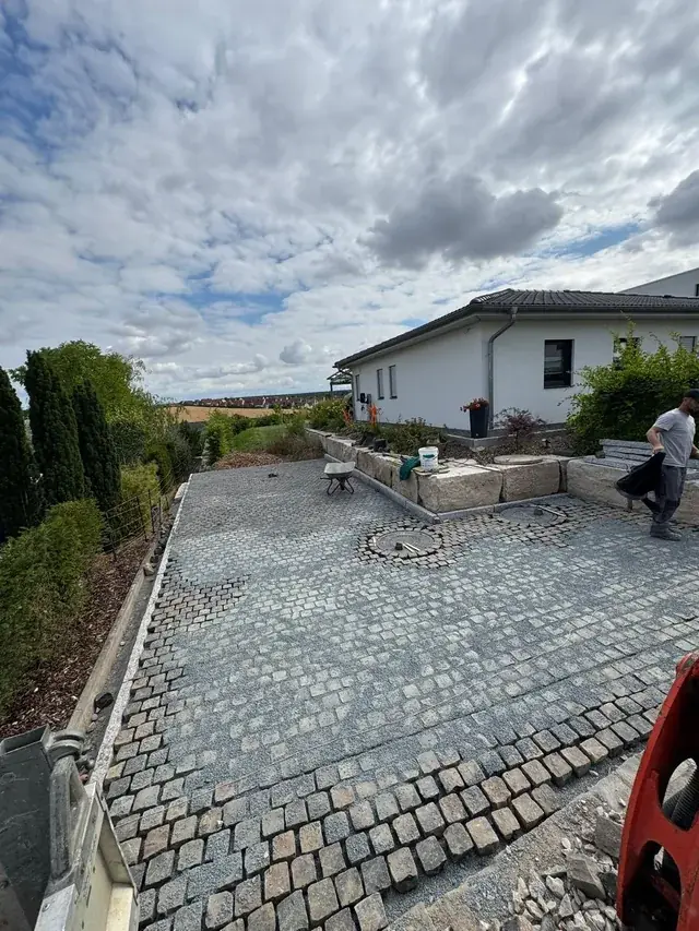 Großflächiges Natursteinpflaster mit eingelegtem Kreismotiv vor einem Bungalow